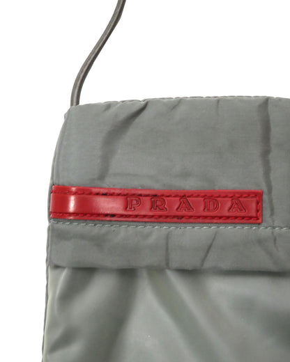 Gray Prada bag with a red logo on a white background