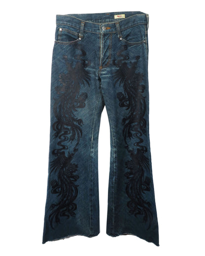 Blue jeans with black floral embroidery on a white background