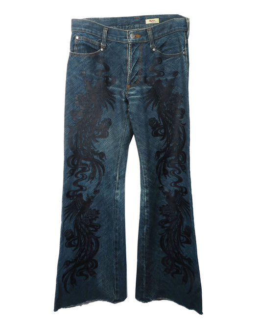 Blue jeans with black floral embroidery on a white background