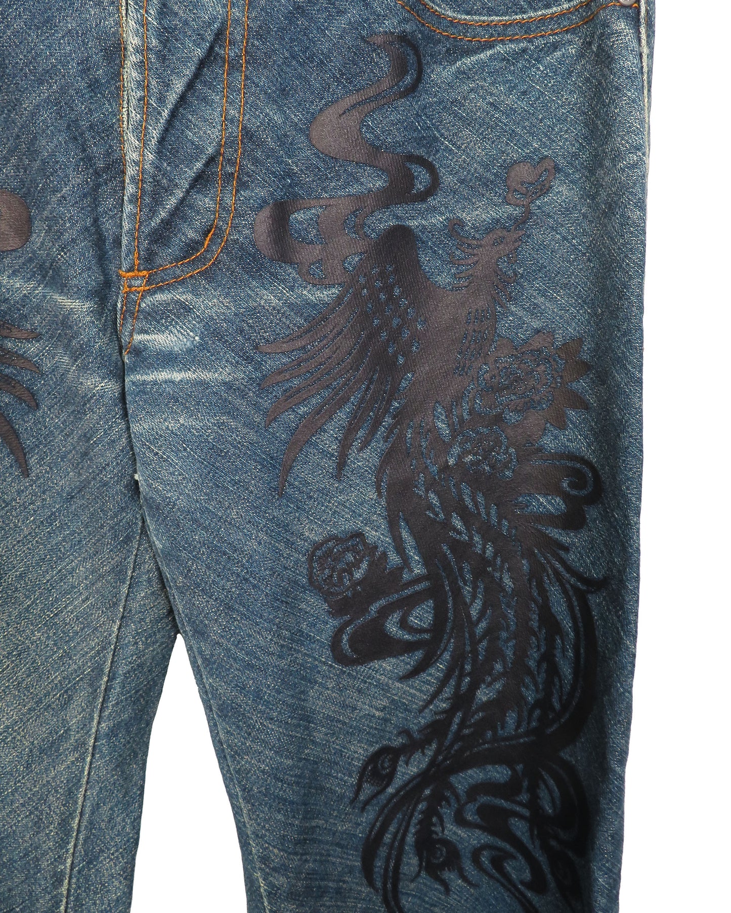 Close-up of blue jeans with a black dragon design on a white background