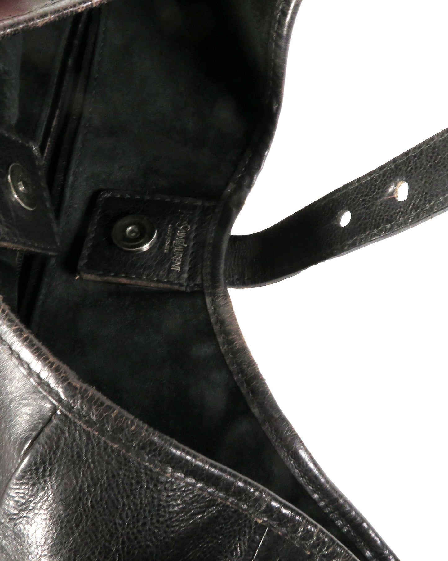 Close-up of a black leather boot with a strap and buckle.
