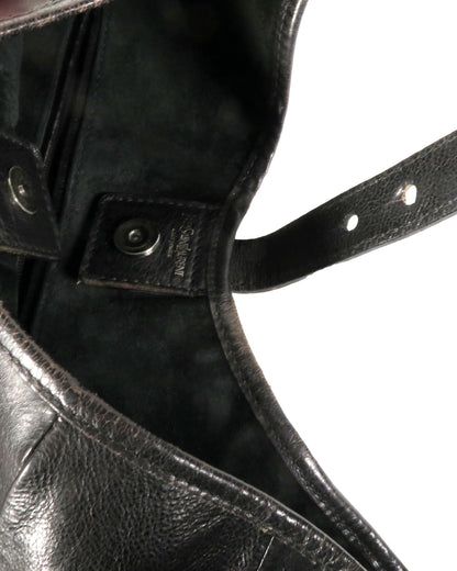 Close-up of a black leather boot with a strap and buckle.
