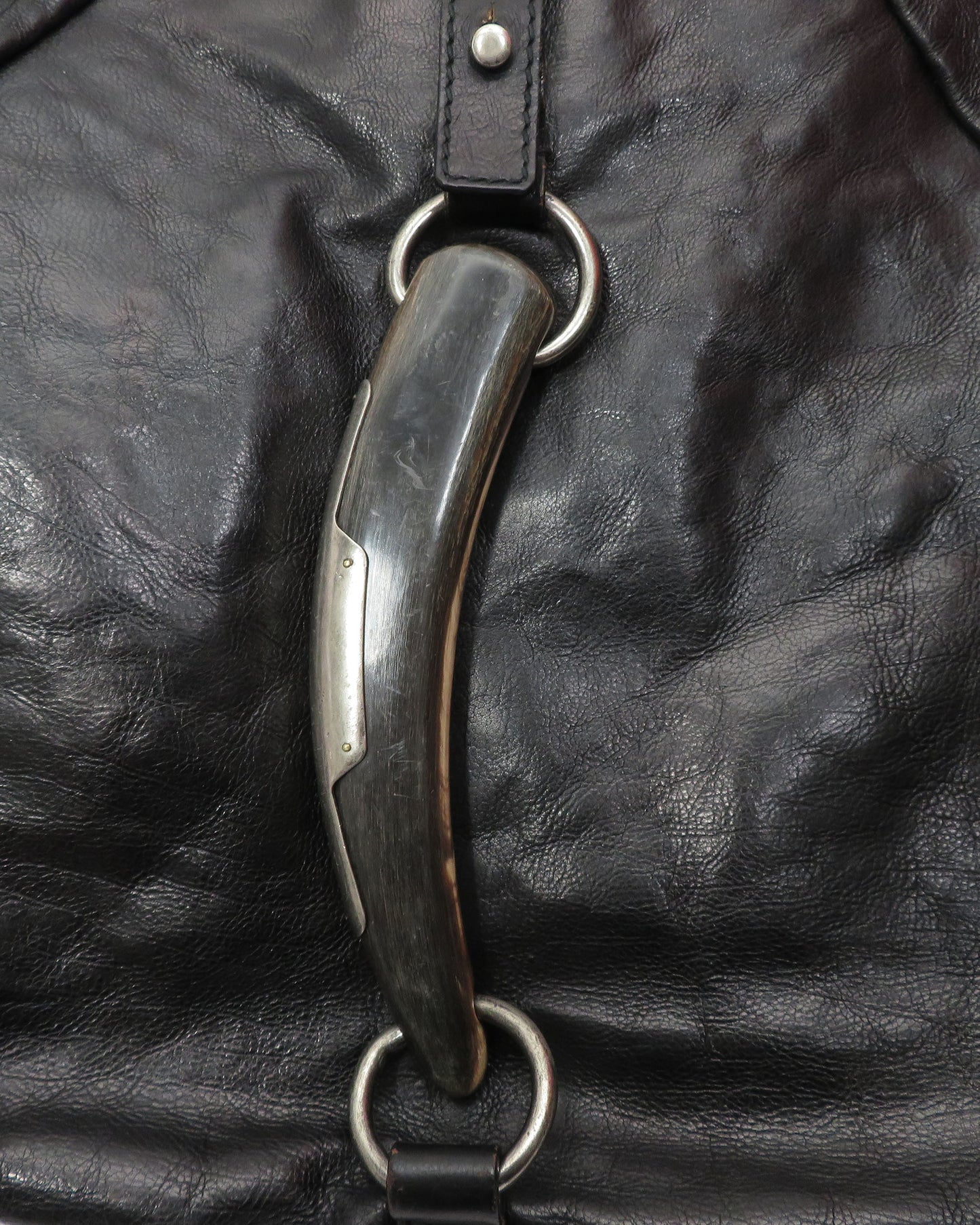 Metal bridle bit on a black leather background