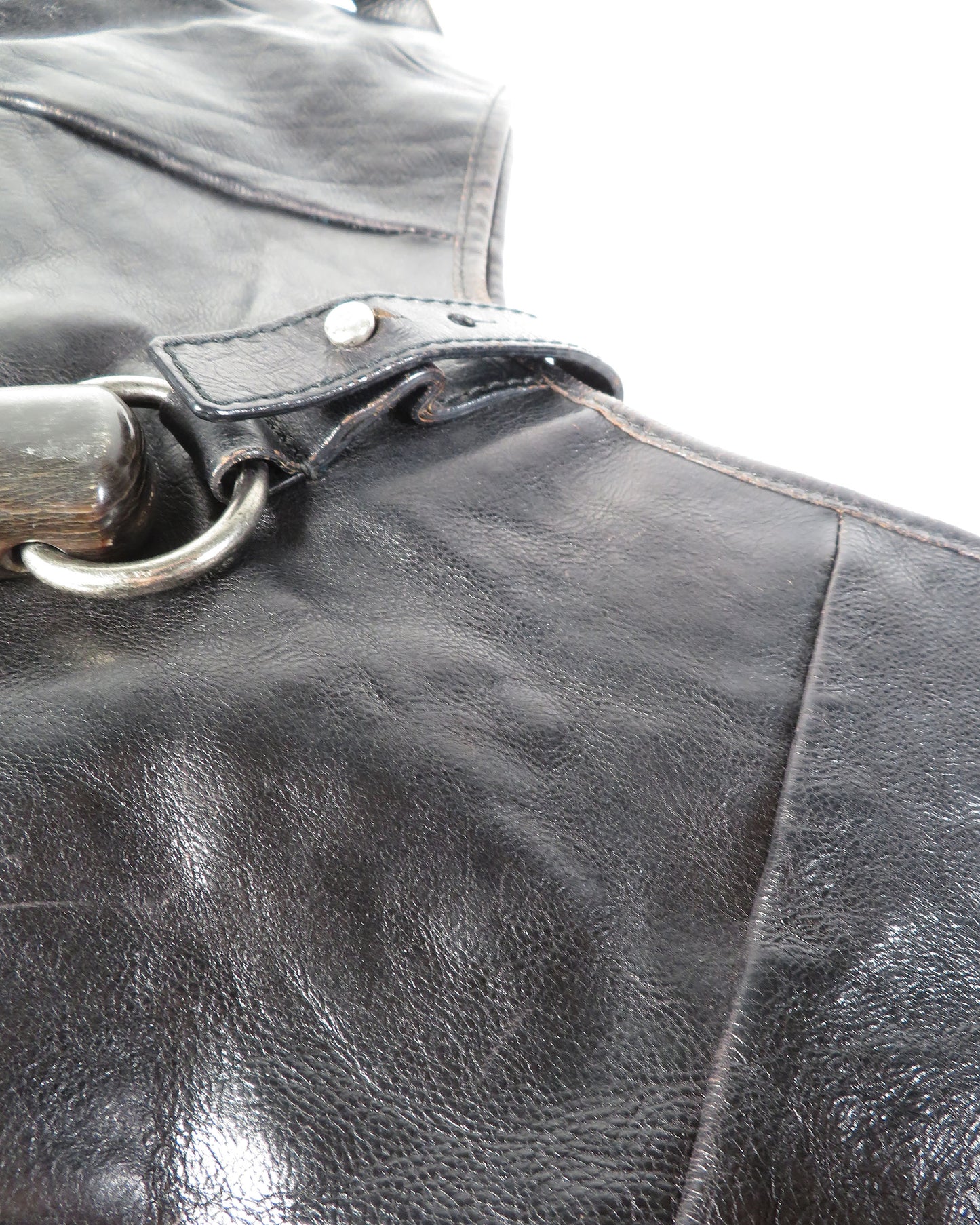 Close-up of a black leather bag with a metal handle.