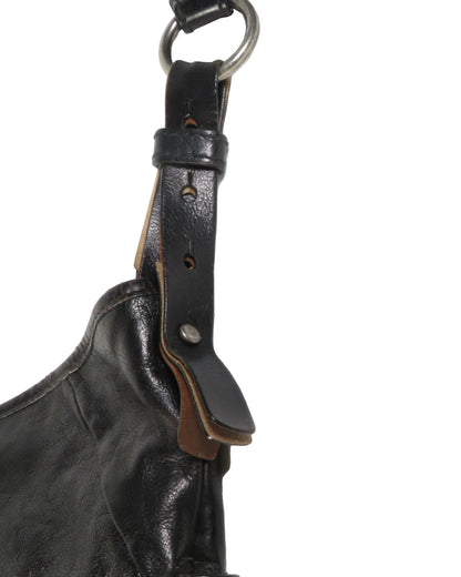 Close-up of a black leather bag with a strap on a white background