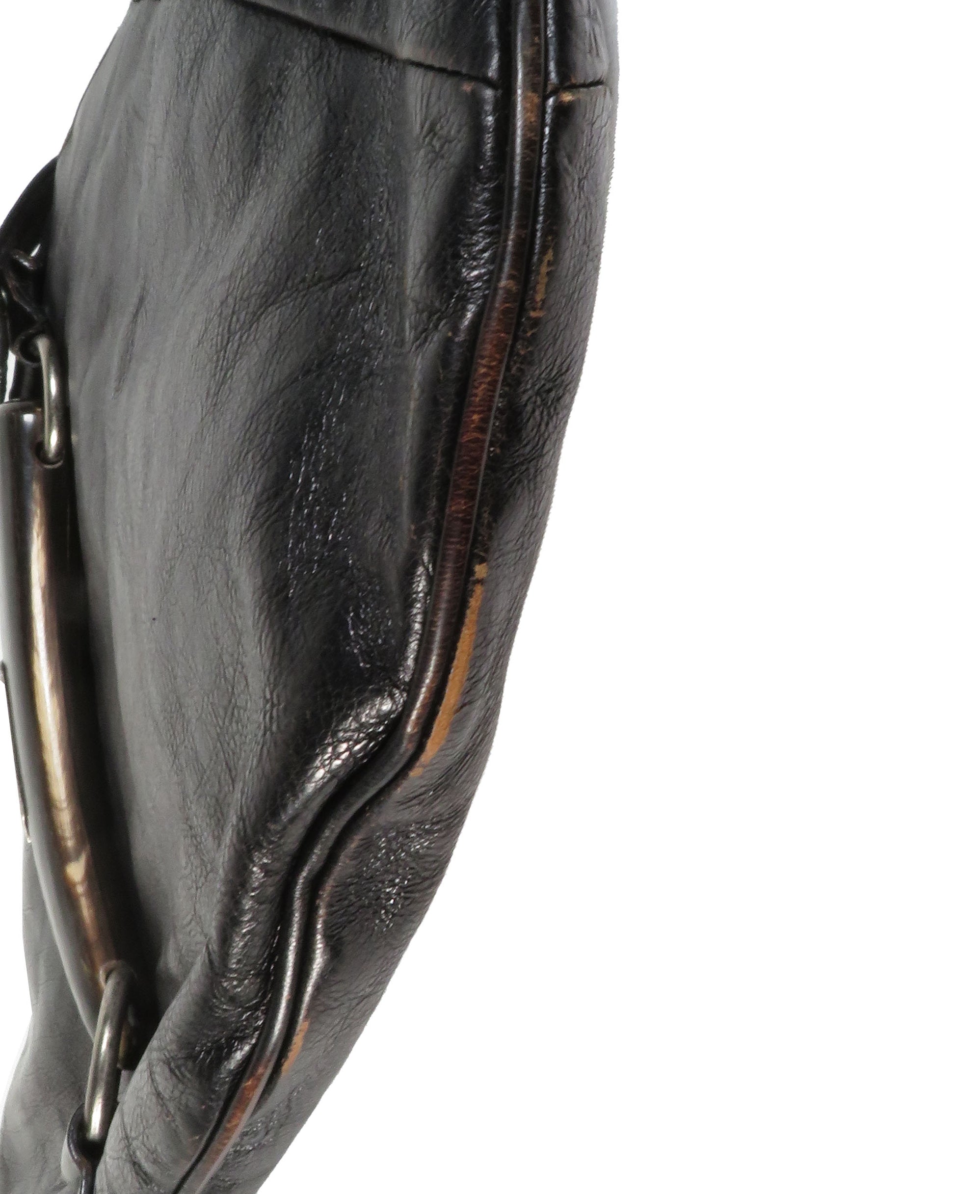 Close-up of a black leather glove with a metal ring on a white background