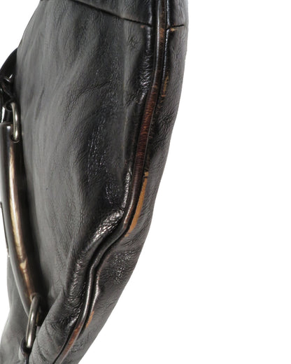 Close-up of a black leather glove with a metal ring on a white background