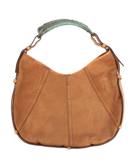 A brown canvas Yves Saint Laurent hobo bag with leather trim and a sculptural metal handle.