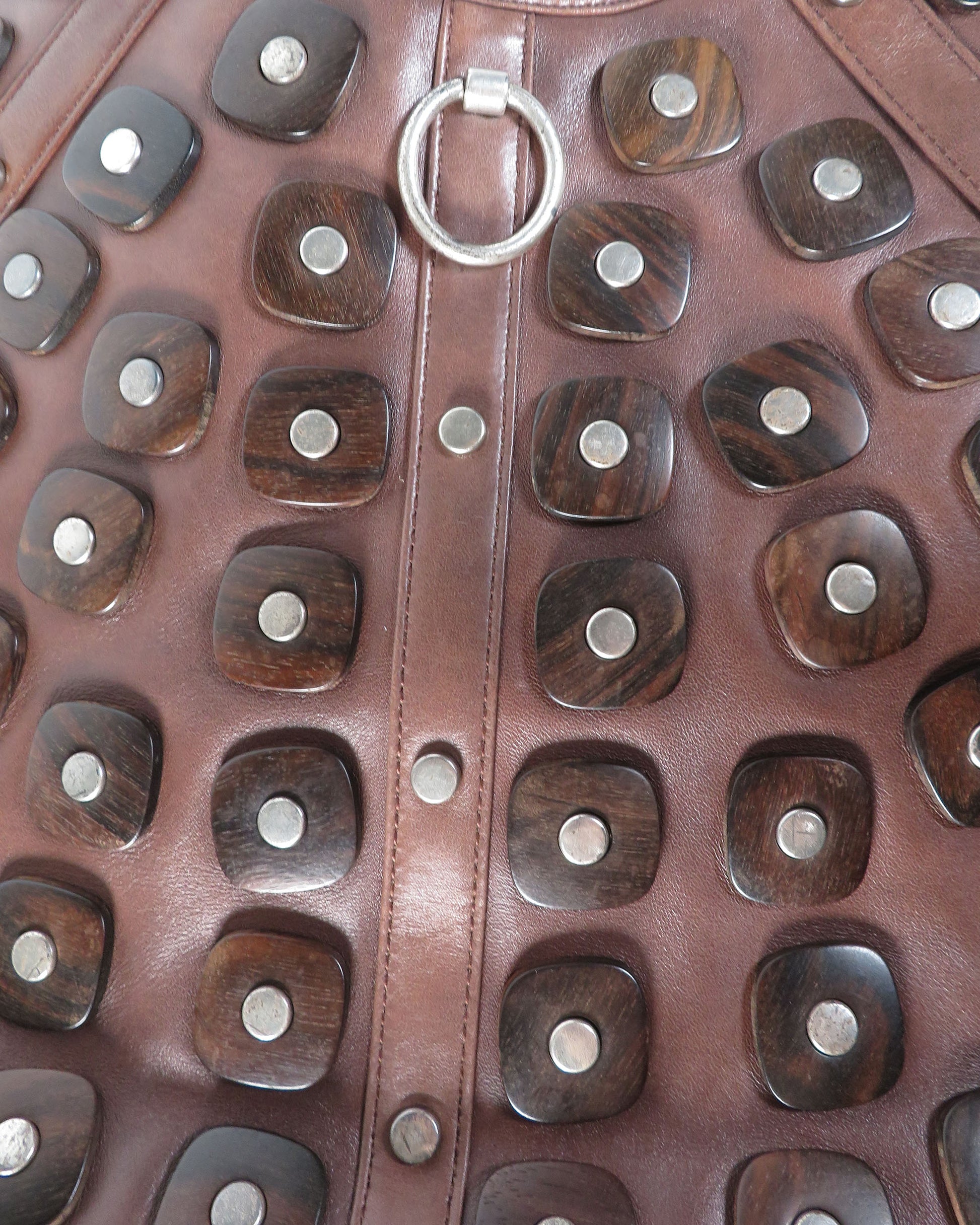 Close-up of a brown leather handbag with wooden accents and silver studs.